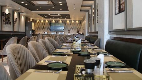 A well-arranged dining space featuring tables with chairs and neatly set cutlery at  BluSalzz Residence, Amritsar